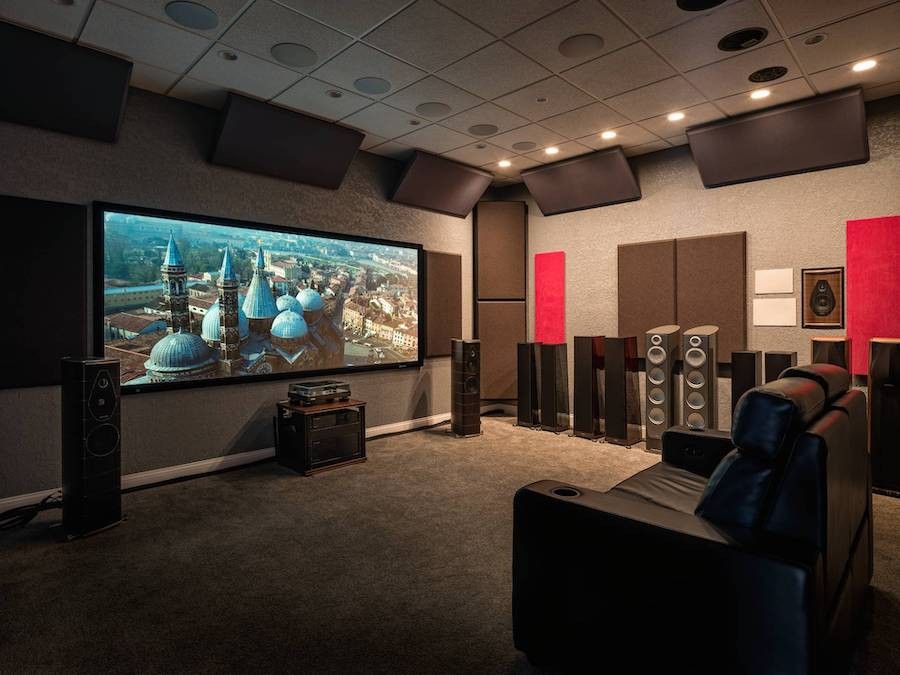 Client’s showroom home theater setup with several floorstanding speakers, a single chair, and a screen featuring blue towers. 